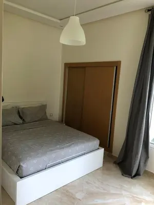 a bedroom with a bed with a wooden door at Appartement moderne CASABAY BEACH Sidi Rahal in Sidi Rahal