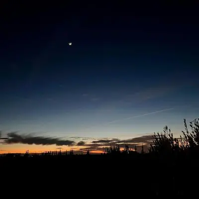 a moon in the sky over a field at sunset at La Casa Blanca • Ecolodge Vert in Oulad Youssef
