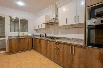 a kitchen with wooden cabinets and a stove top oven at TT Holidays 3BR Racine Casablanca in Casablanca