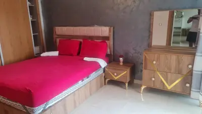 a bedroom with a bed with red sheets and a mirror at superbe appartement vue piscine in Bouznika