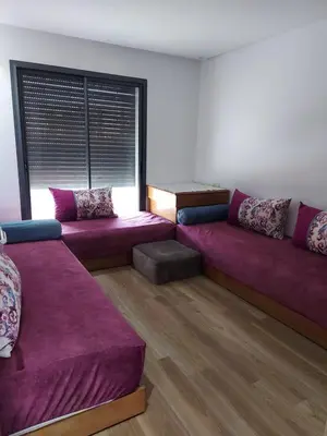 a living room with purple couches and a window at Dahlia Sidi rahal in Sidi Rahal