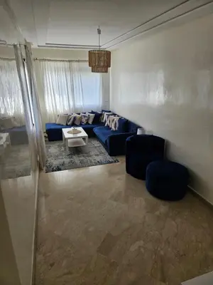 a living room with a blue couch and two chairs at Bel appartement en bord de mer in Casablanca