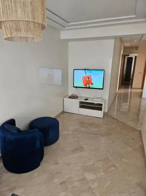 a living room with a tv and a blue chair at Bel appartement en bord de mer in Casablanca
