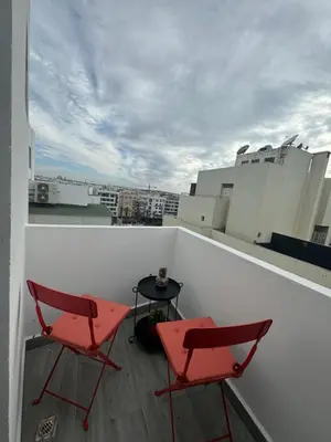 two red chairs and a table on a balcony at au cœur de la Corniche in Casablanca
