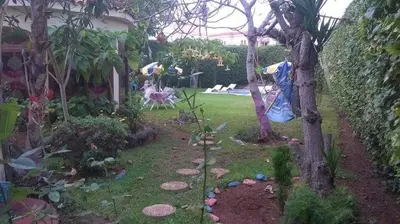 a garden with a tree and people in the yard at Villa entièrement meublée à louer à Mohammedia in Mohammedia