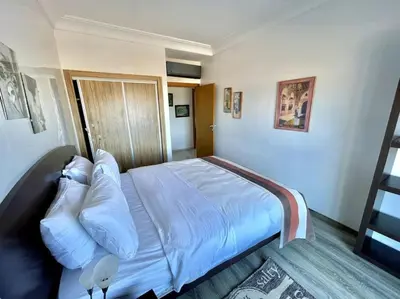 a bedroom with a bed with white sheets and pillows at Miramar Luxury apartment Front Beach View in Mohammedia