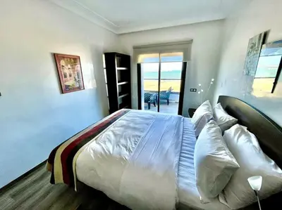 a bedroom with a bed with white sheets and pillows at Miramar Luxury apartment Front Beach View in Mohammedia