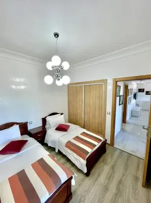 a hotel room with two beds and a chandelier at Miramar Luxury apartment Front Beach View in Mohammedia