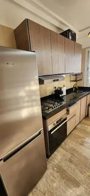 a kitchen with a stainless steel refrigerator and wooden cabinets at Beautiful beachfront apartment in Rabat