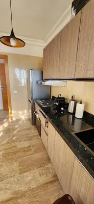 a kitchen with wooden cabinets and a black counter top at Beautiful beachfront apartment in Rabat