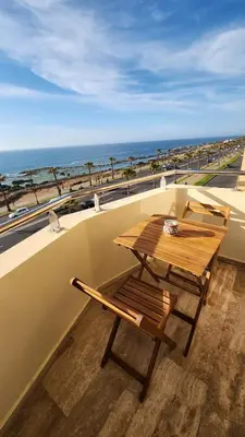 a wooden table and bench on a balcony with the beach at Beautiful beachfront apartment in Rabat