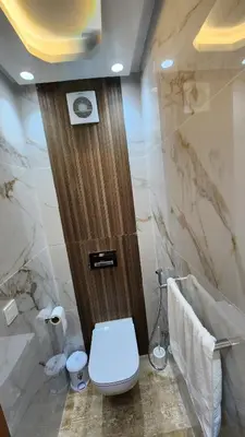 a bathroom with a toilet and a wooden door at Beautiful beachfront apartment in Rabat