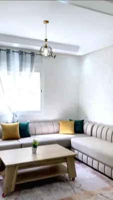 a living room with a couch and a table at Appartement avec piscine in Bouznika