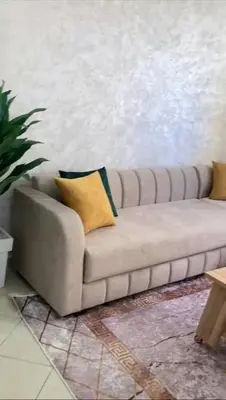 a couch in a living room with a yellow pillow at Appartement avec piscine in Bouznika