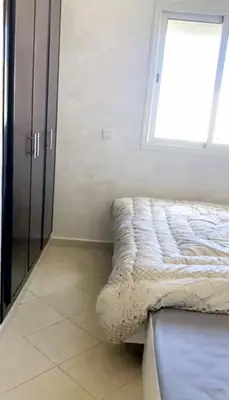 a bedroom with a bed and a window at Appartement avec piscine in Bouznika
