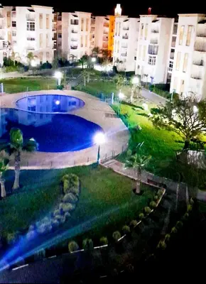 a large swimming pool in a city at night at Appartement avec piscine in Bouznika