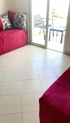 a living room with a red couch and a table at Appartement avec piscine in Bouznika