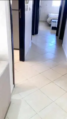 a hallway with a white tiled floor at Appartement avec piscine in Bouznika