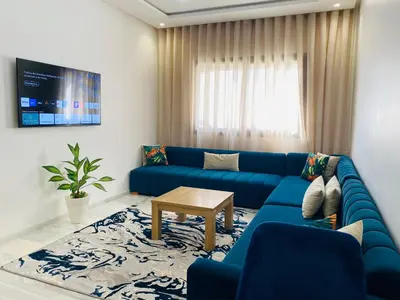 a living room with a blue couch and a table at Glorious NOUACEUR in Nouaceur