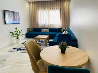 a living room with a blue couch and a table at Glorious NOUACEUR in Nouaceur