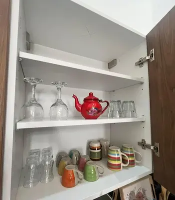 a cupboard filled with glasses and a red tea pot at Take the Best Rest Near the airport in Nouaceur