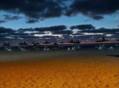 a group of chairs and umbrellas on the beach at Nice Apartment in Blanca Beach in Sidi Rahal