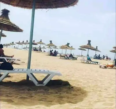 a person sitting on a beach under an umbrella at Nice Apartment in Blanca Beach in Sidi Rahal