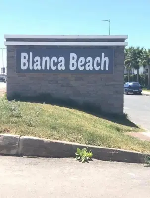 a sign for a beach with a plant in the sidewalk at Nice Apartment in Blanca Beach in Sidi Rahal