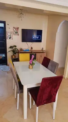 a white dining room table with chairs and a tv at appartamento in residenza protetta con piscina in Mohammedia
