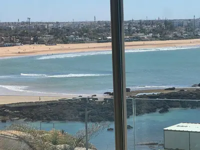a view of a beach and the ocean from a window at Appartement vue sur mer résidence Les vagues des sablettes Mansouria in Mohammedia