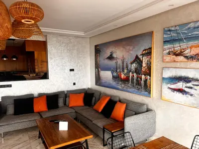 a living room with a gray couch and orange pillows at Appartement vue sur mer résidence Les vagues des sablettes Mansouria in Mohammedia