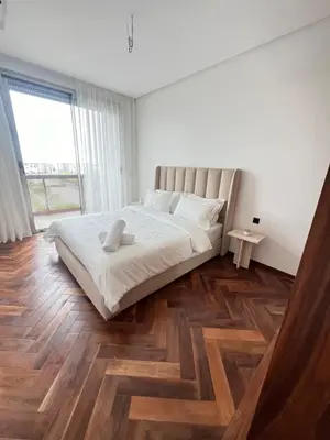 a white bedroom with a large bed and wooden floors at Casa finance city - Anfa Park - CFC in Casablanca