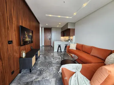 a living room with an orange couch and a kitchen at Casa finance city - Anfa Park - CFC in Casablanca