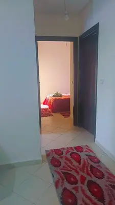a room with a red rug on the floor and a bedroom at Bouznika in Bouznika