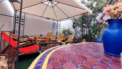 a table with a blue vase with flowers in it at Taddart, Maison de vacances in Temara