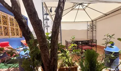 a patio with a table and chairs and an umbrella at Taddart, Maison de vacances in Temara