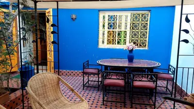 a table and chairs in a room with a blue wall at Taddart, Maison de vacances in Temara