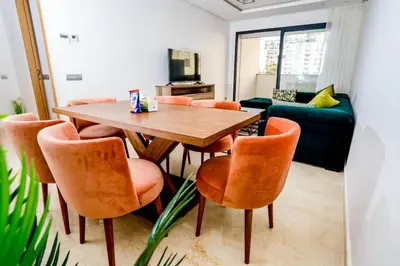 a dining room with a wooden table and orange chairs at Moderne et luxueux in Rabat