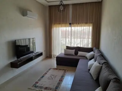 a living room with a couch and a tv at Vacances Soleil Piscine & Plage Bouznika in Bouznika