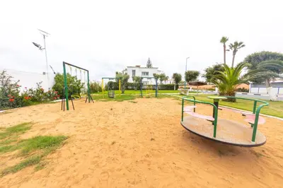an empty park with a swing set in the dirt at Villa en bord de plage, située dans une résidence à El Mansouria, idéale pour une grande famille ou pour des personnes seules in Mansouria