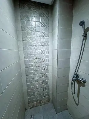 a bathroom with a shower with white tiles at Appartement spacieux et calme à proximité de la mer et la gare agdal in Rabat