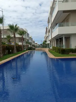 a large blue swimming pool in front of a building at Heaven Beach Front Apartment 2 Br in Sidi Rahal