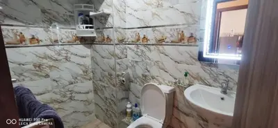 a marble bathroom with a toilet and a sink at Appartement Proche plage Bouznika Bouznika in Bouznika