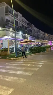 a person walking across a parking lot at night at Résidence Balnéaire, Appartement 2 Chambres in Mansouria