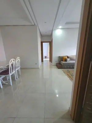 a living room with a couch and a table and chairs at Résidence Balnéaire, Appartement 2 Chambres in Mansouria