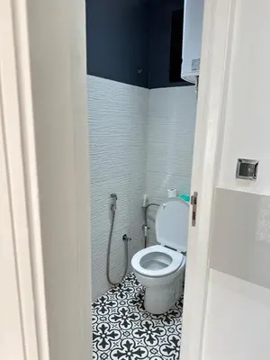 a bathroom with a toilet with a black and white tile floor at Chambre à Agdal Rabat dans un appartement partagé -king bed- in Rabat