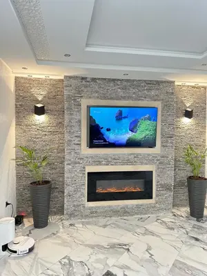 a living room with a tv on a stone wall at Chambre à Agdal Rabat dans un appartement partagé -king bed- in Rabat