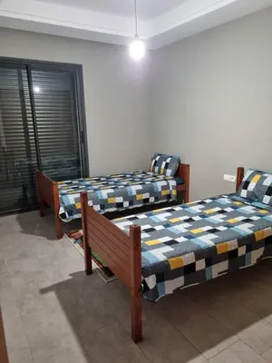 a room with two beds and a bench in it at Bel appartement à Harhoura in Oulad Kerroum
