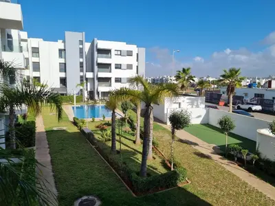 a view of a courtyard with palm trees and a building at Bel appartement à Harhoura in Oulad Kerroum