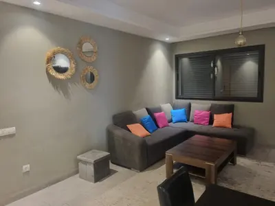 a living room with a couch with colorful pillows at Bel appartement à Harhoura in Oulad Kerroum